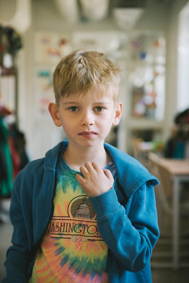 a boy with blonde hair wearing a blue hoodie