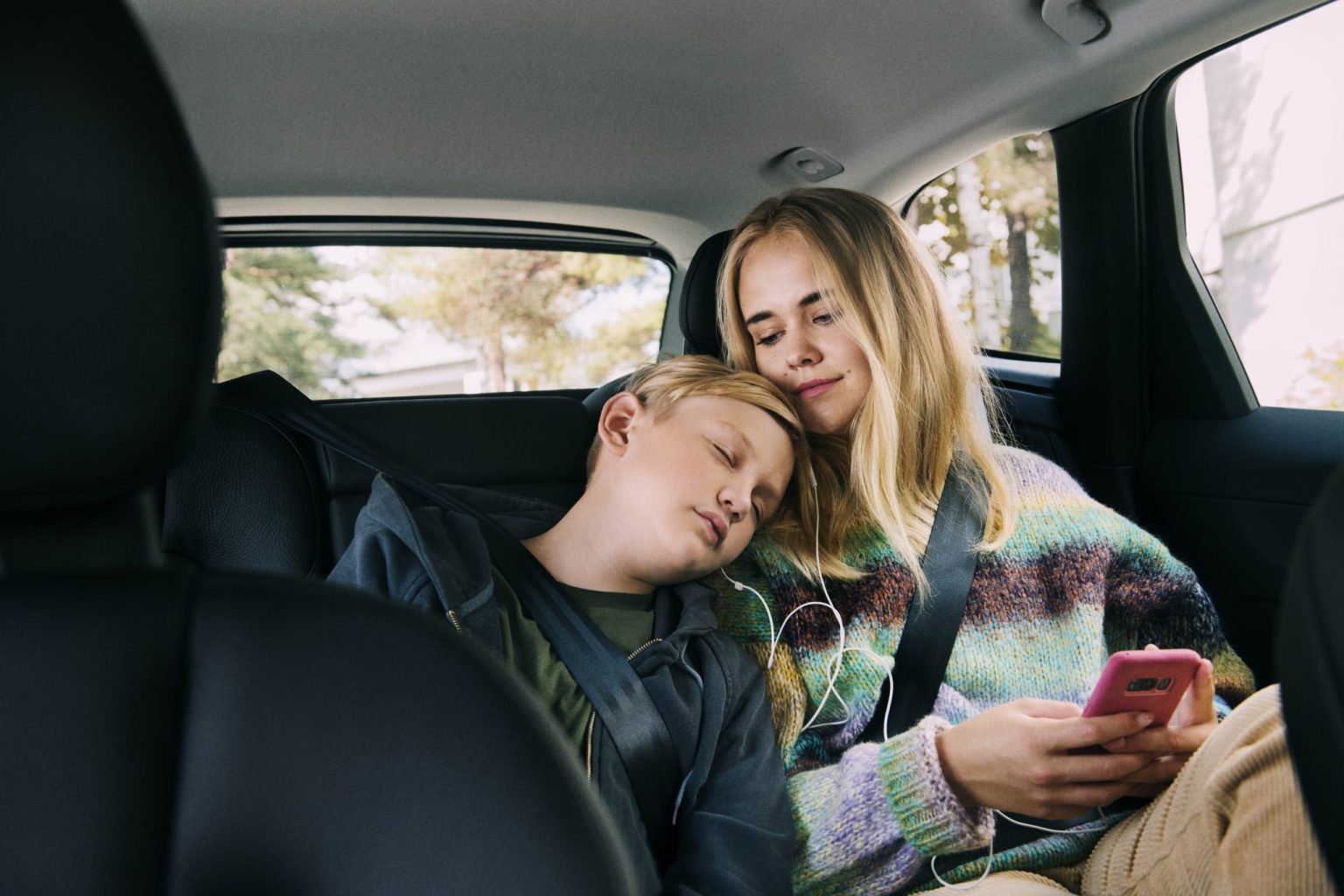 a woman and boy sleeping in a car