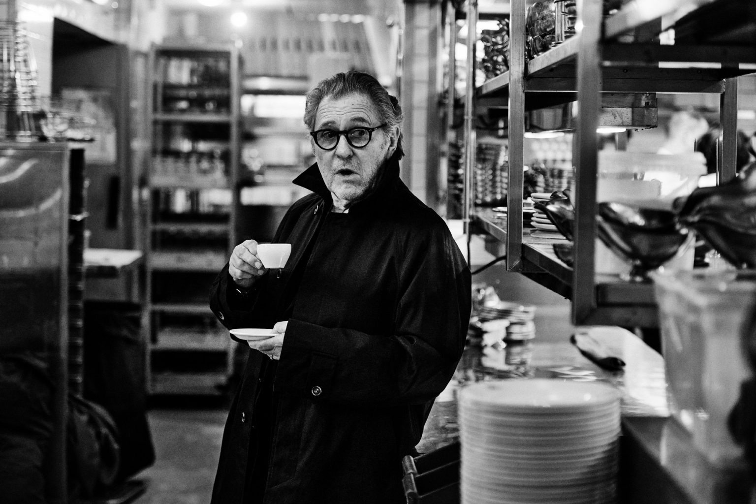 a man in a black coat holding a cup and saucer