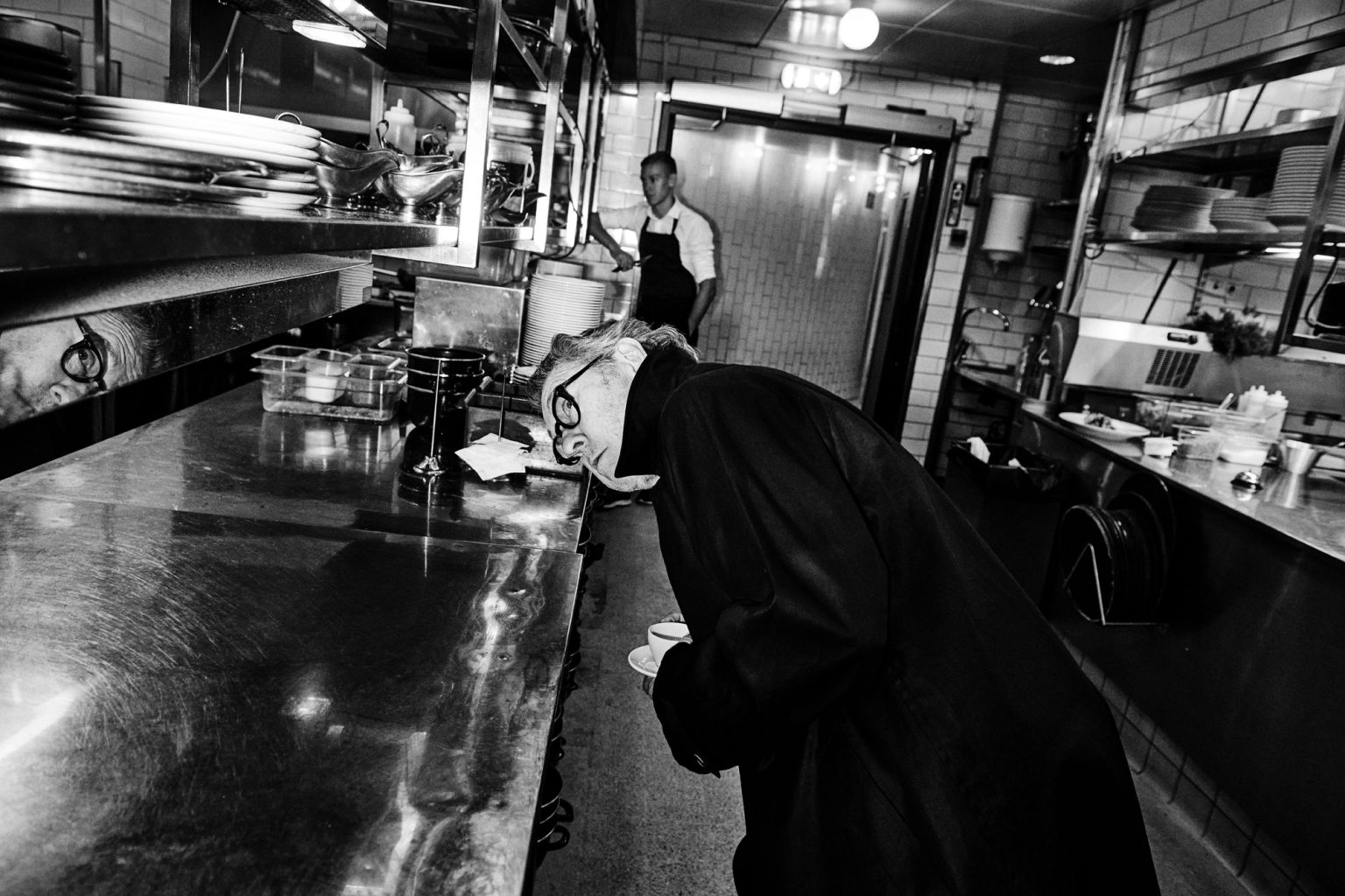 a man in a black robe smelling a cup of coffee