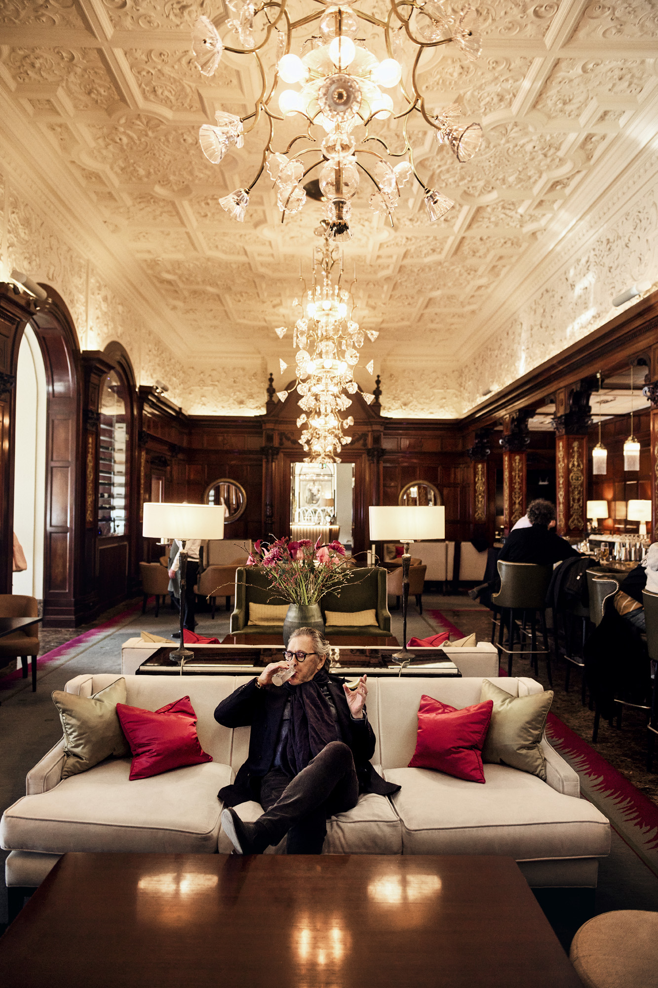 a man sitting on a couch in a room with a chandelier