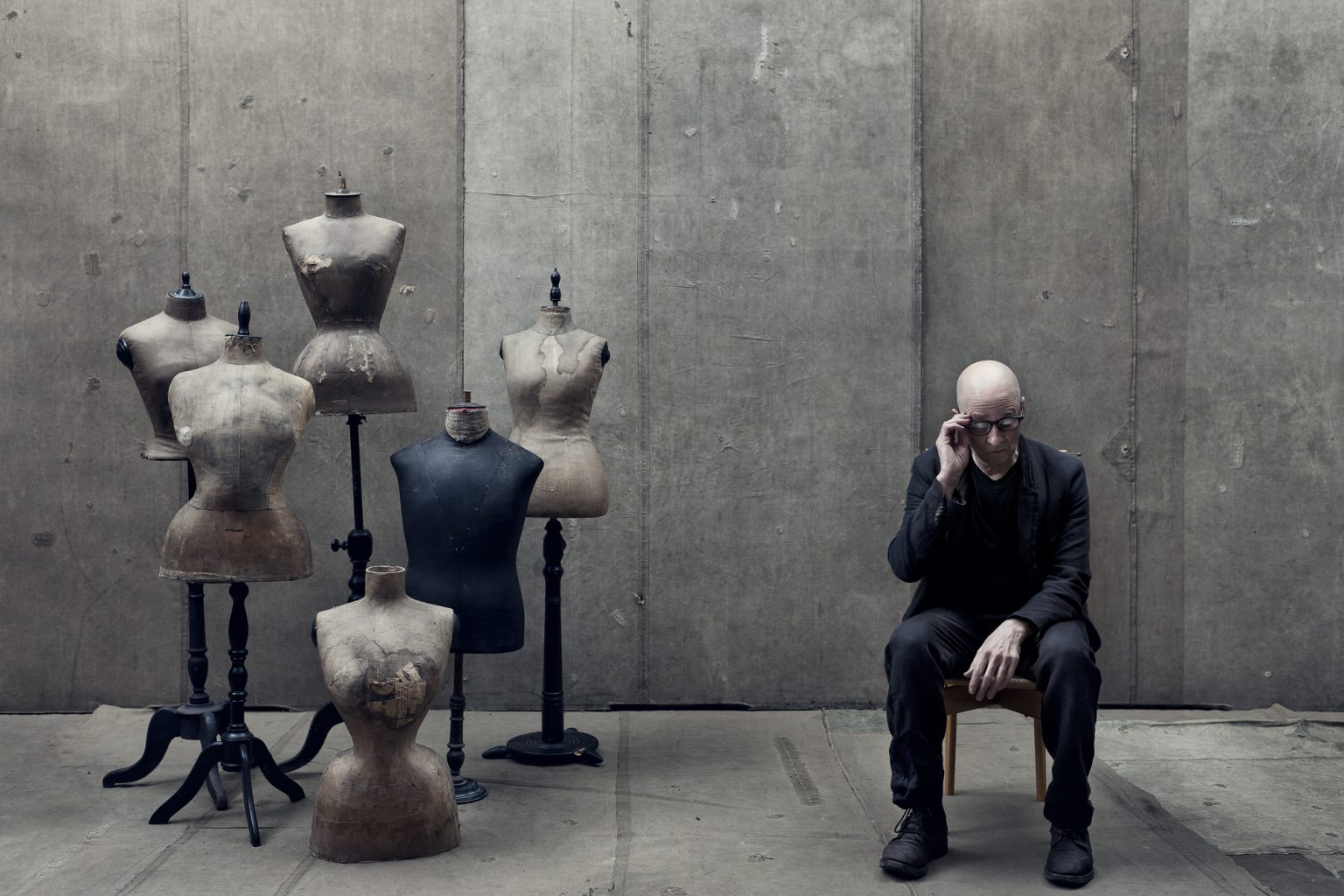 a man sitting in a chair with a group of mannequins in front of him