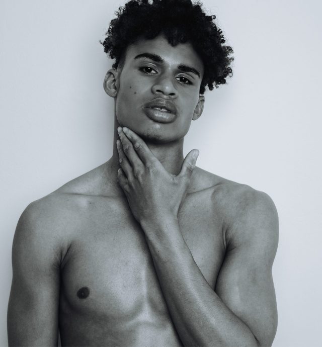 a man with curly hair holding his neck