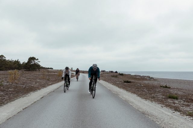 a group of people riding bicycles on a road near water