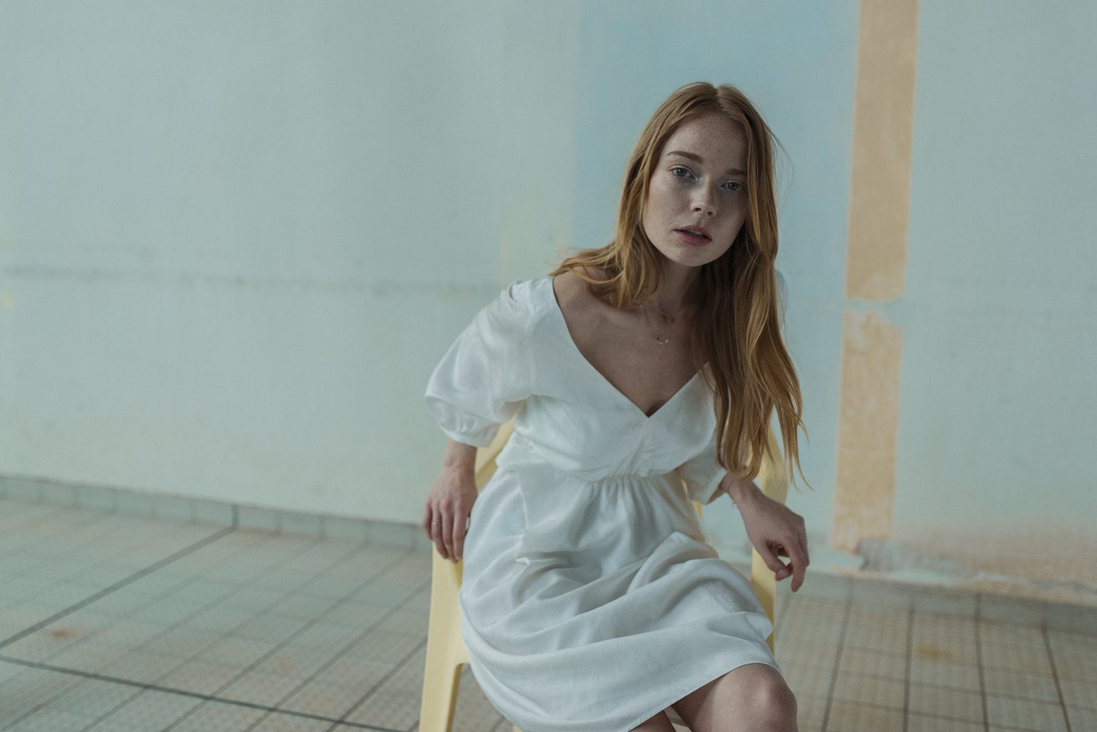 a woman in a white dress sitting on a yellow chair