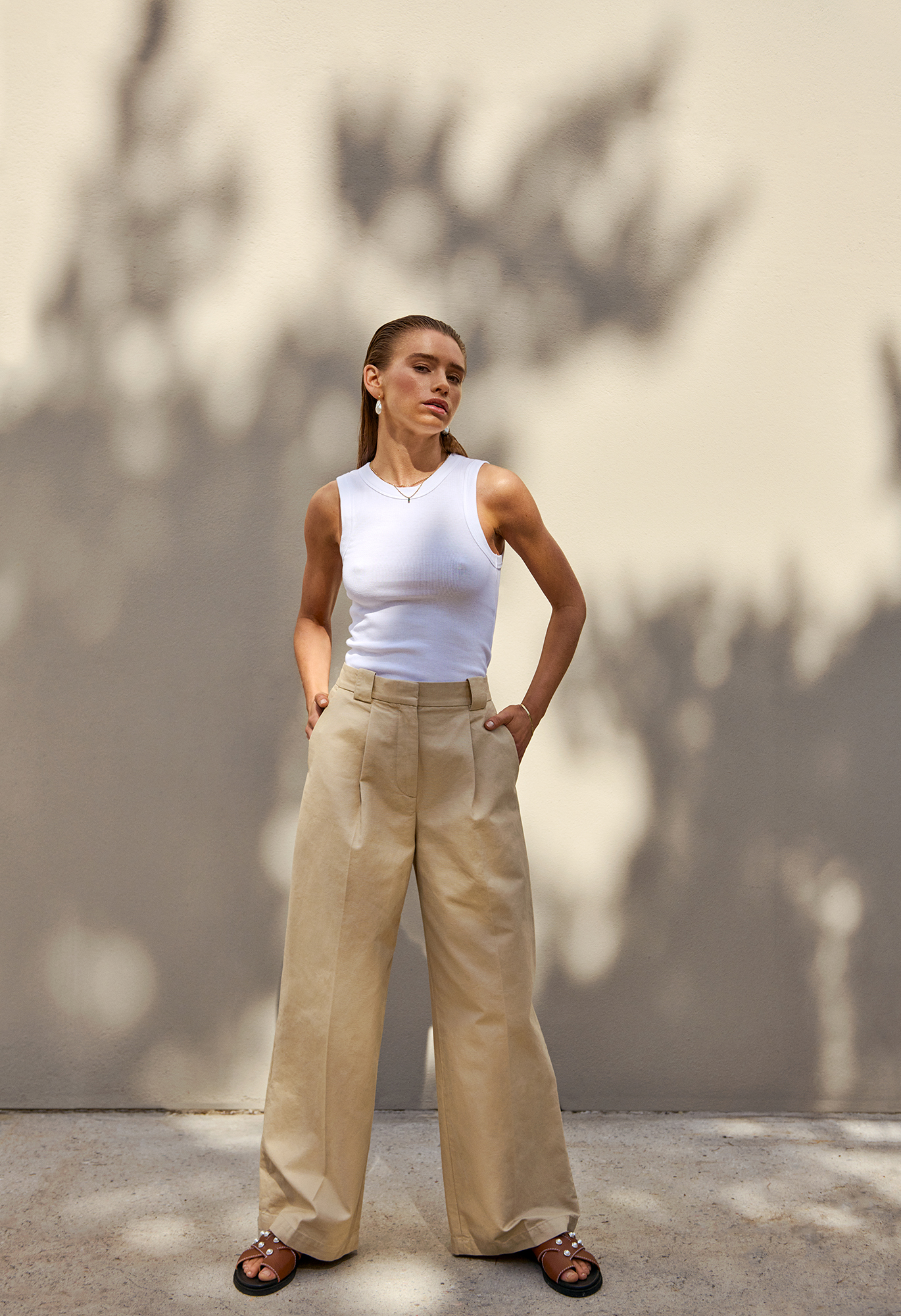 a woman in a white tank top and beige pants