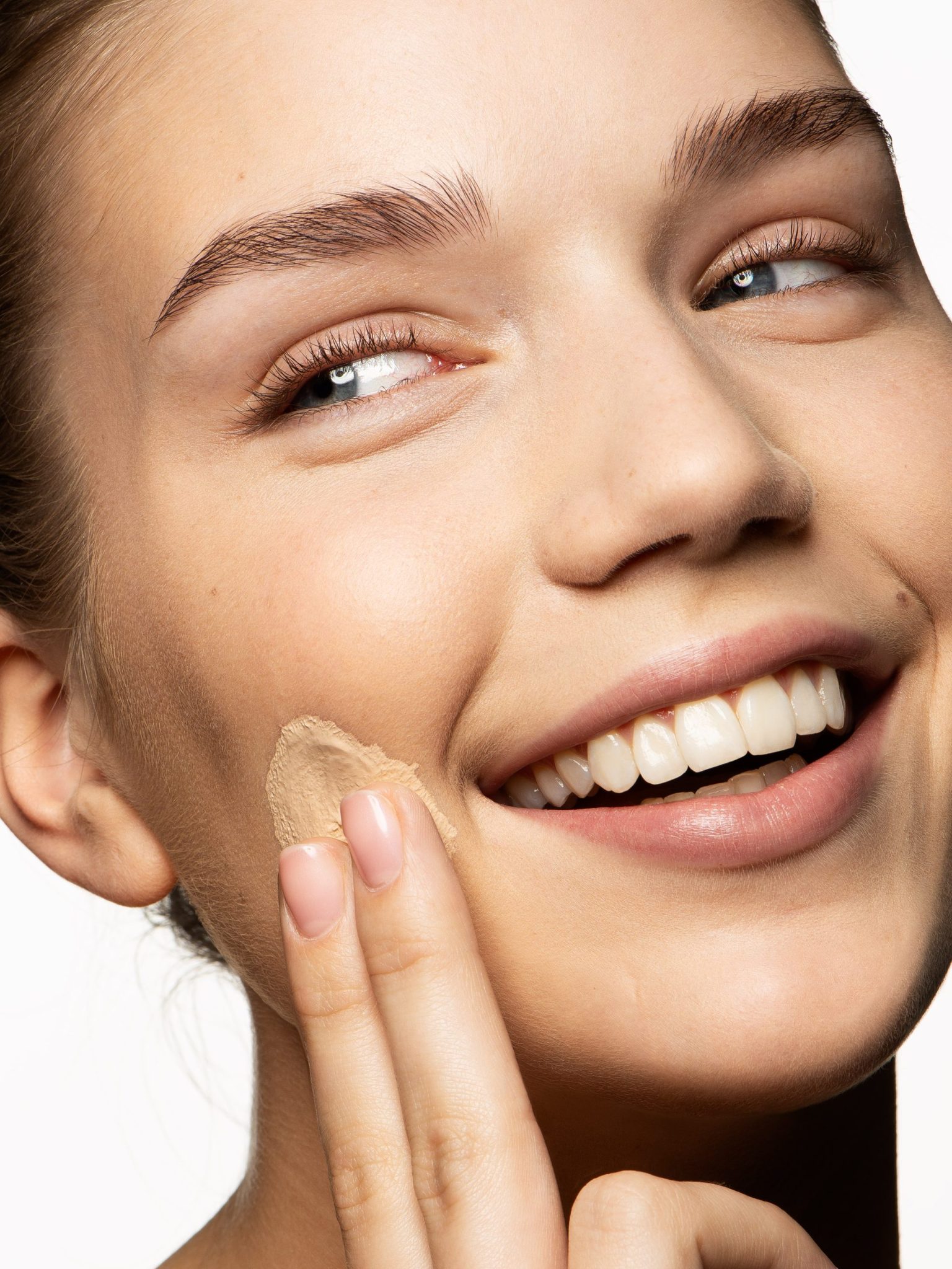 a woman smiling with a foundation on her face