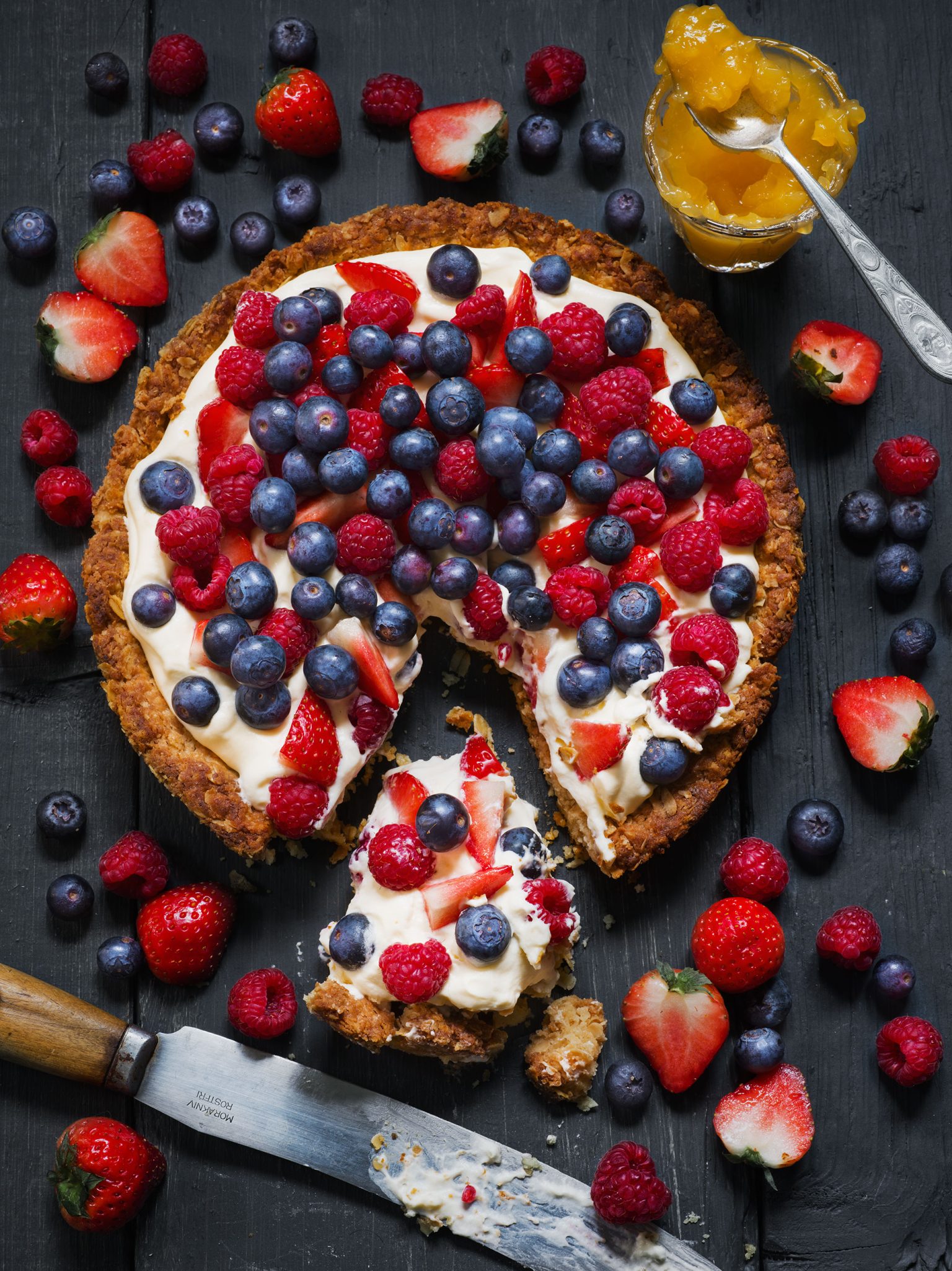 a pie with berries on top and a knife