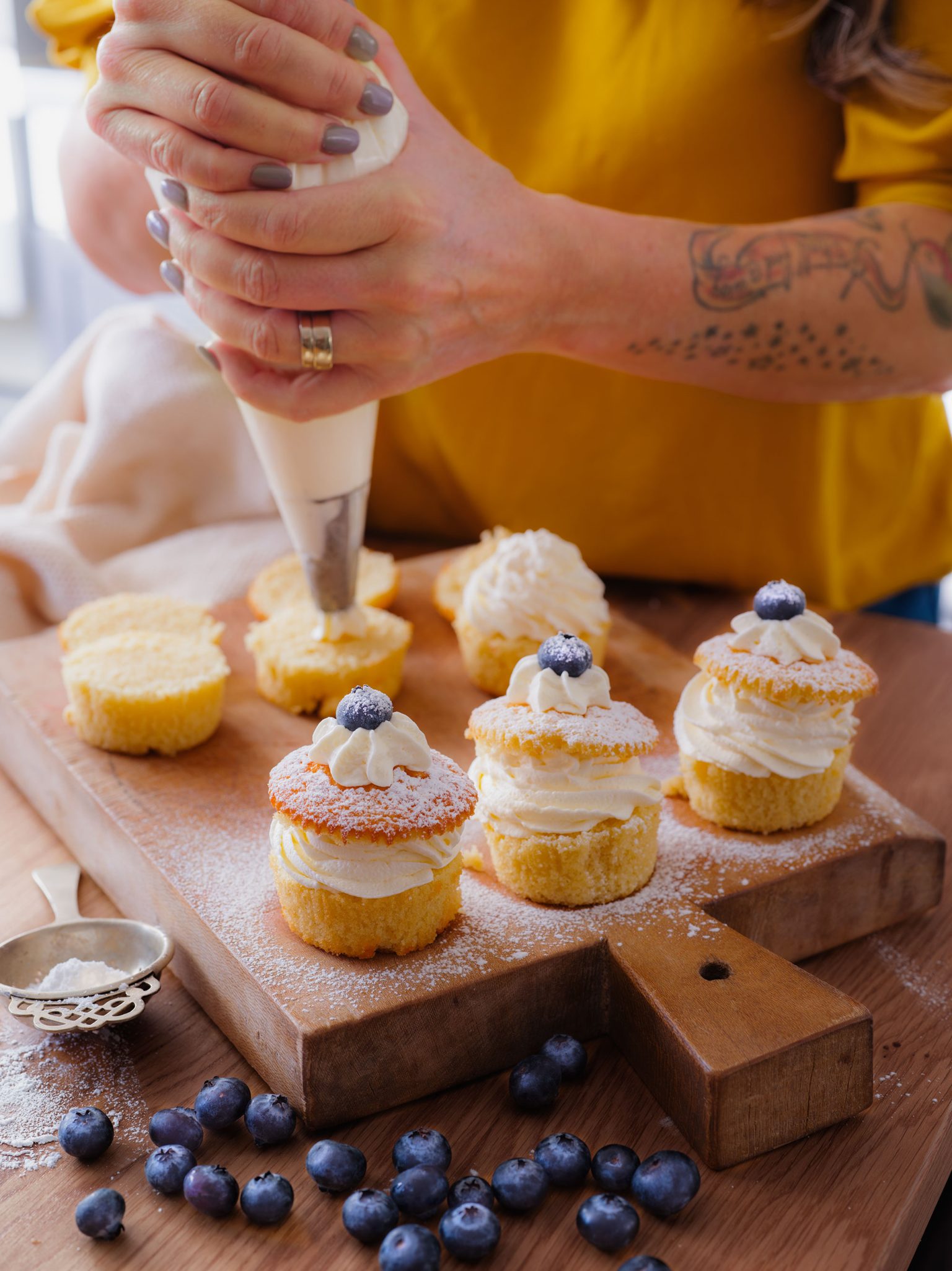 a person using a pastry bag to decorate cupcakes
