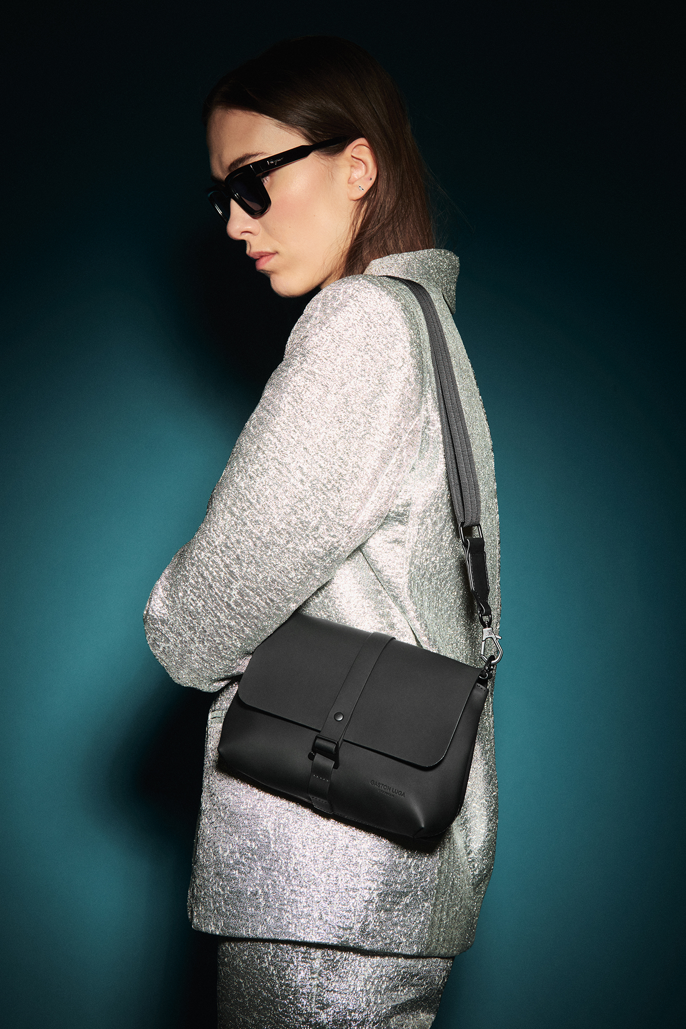 a woman wearing sunglasses and a silver jacket with a black purse