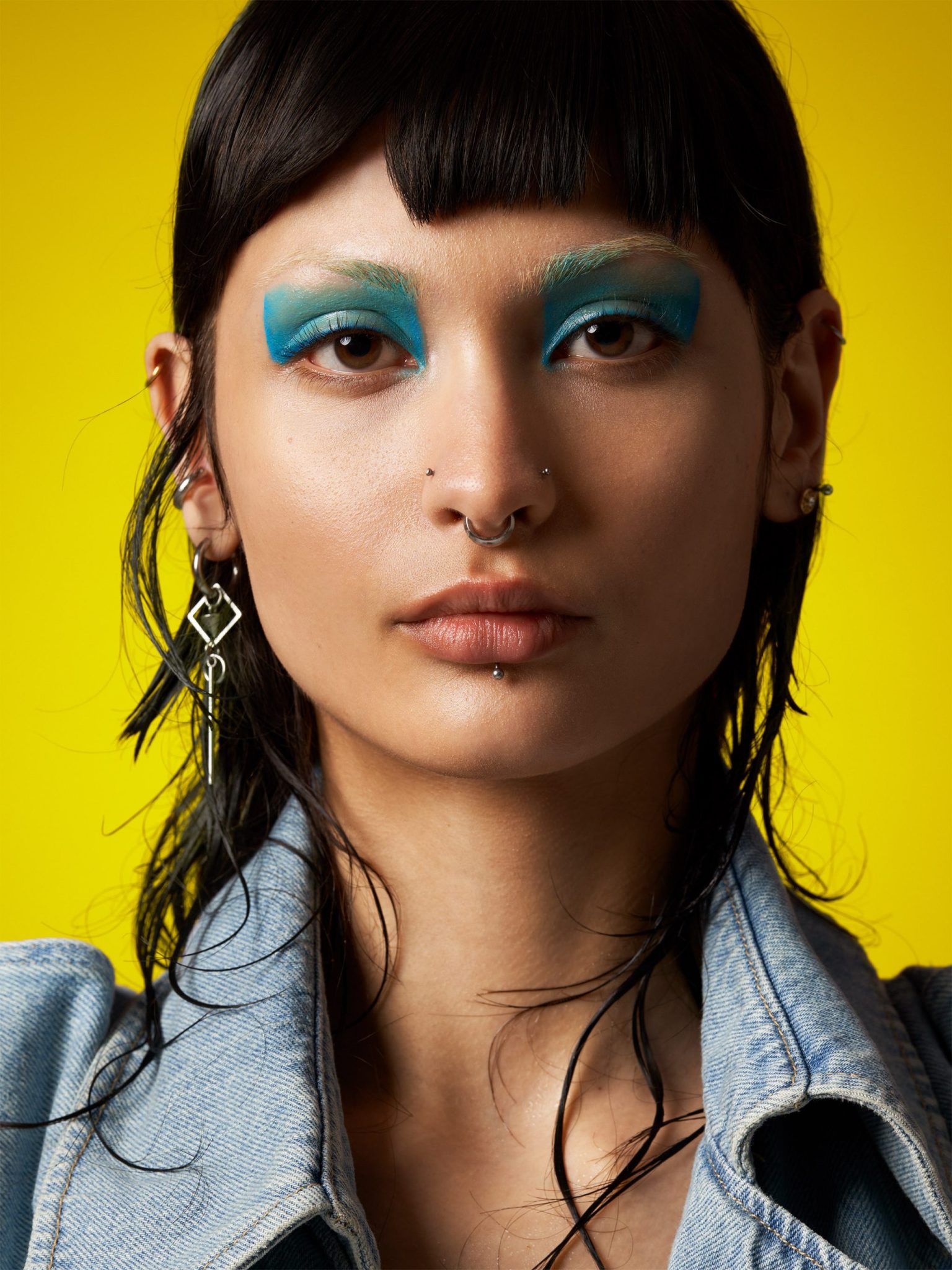 a woman with blue makeup and piercings
