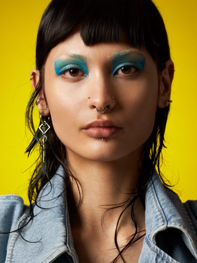 a woman with blue makeup and piercings