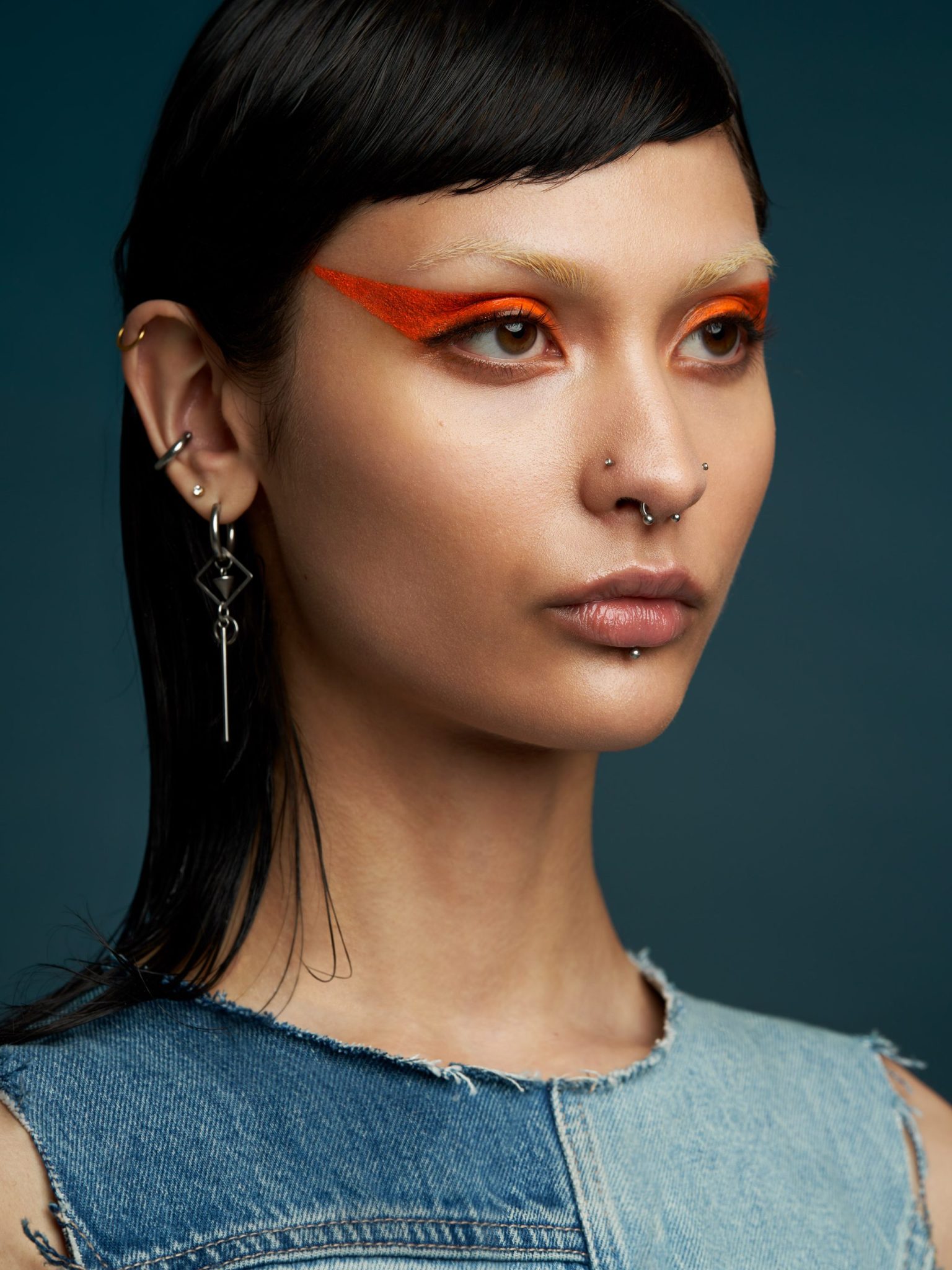a woman with orange eye makeup and piercings