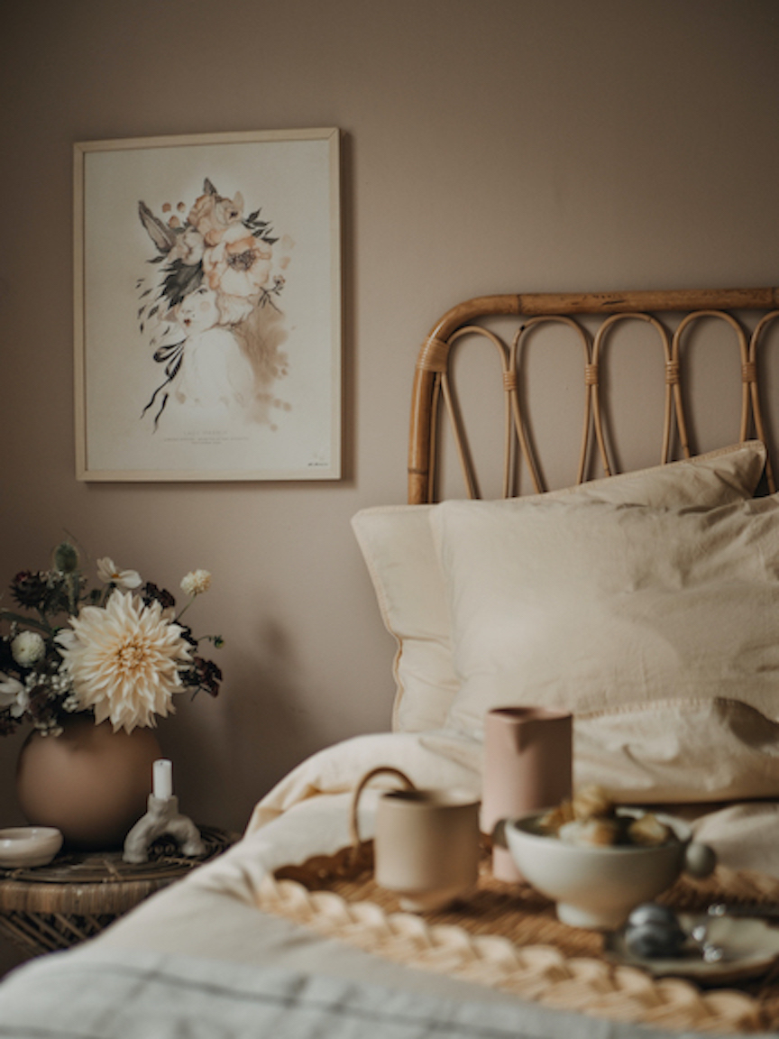 a bed with a basket of flowers and a painting on the wall
