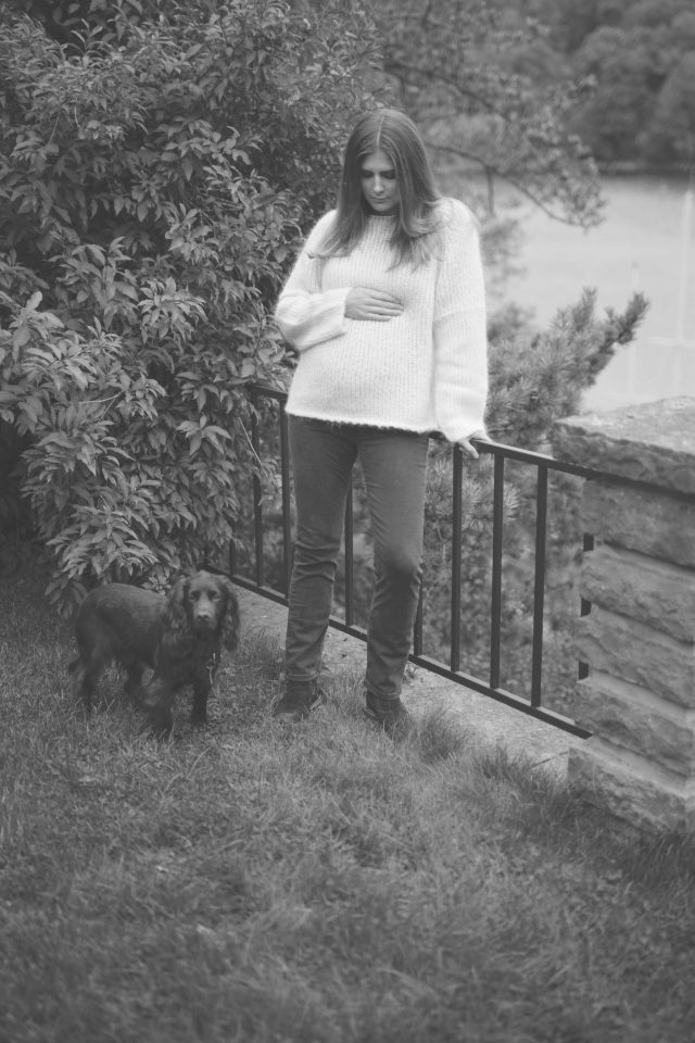 a woman standing next to a fence with a dog