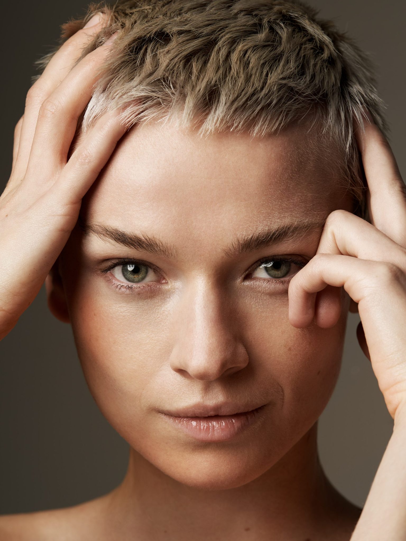a woman with short hair touching her head