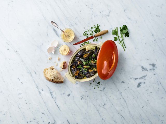 a bowl of mussels and bread with a red lid