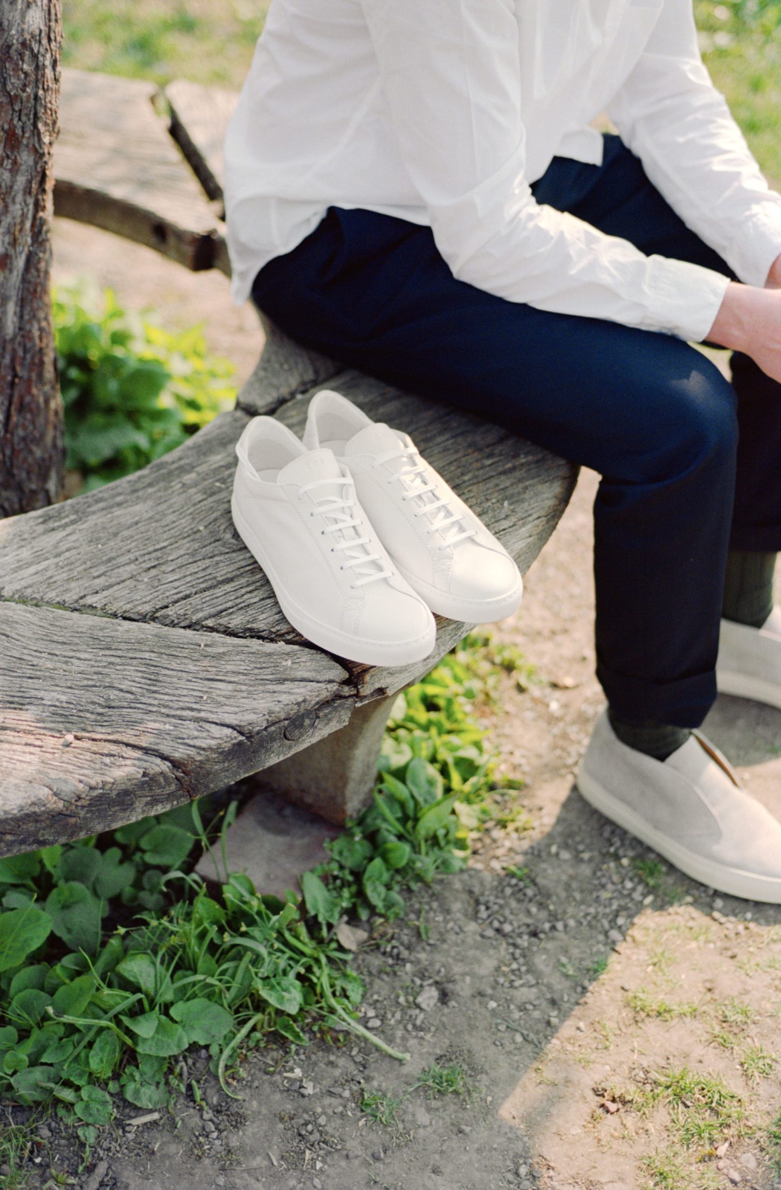 a person sitting on a bench with white shoes