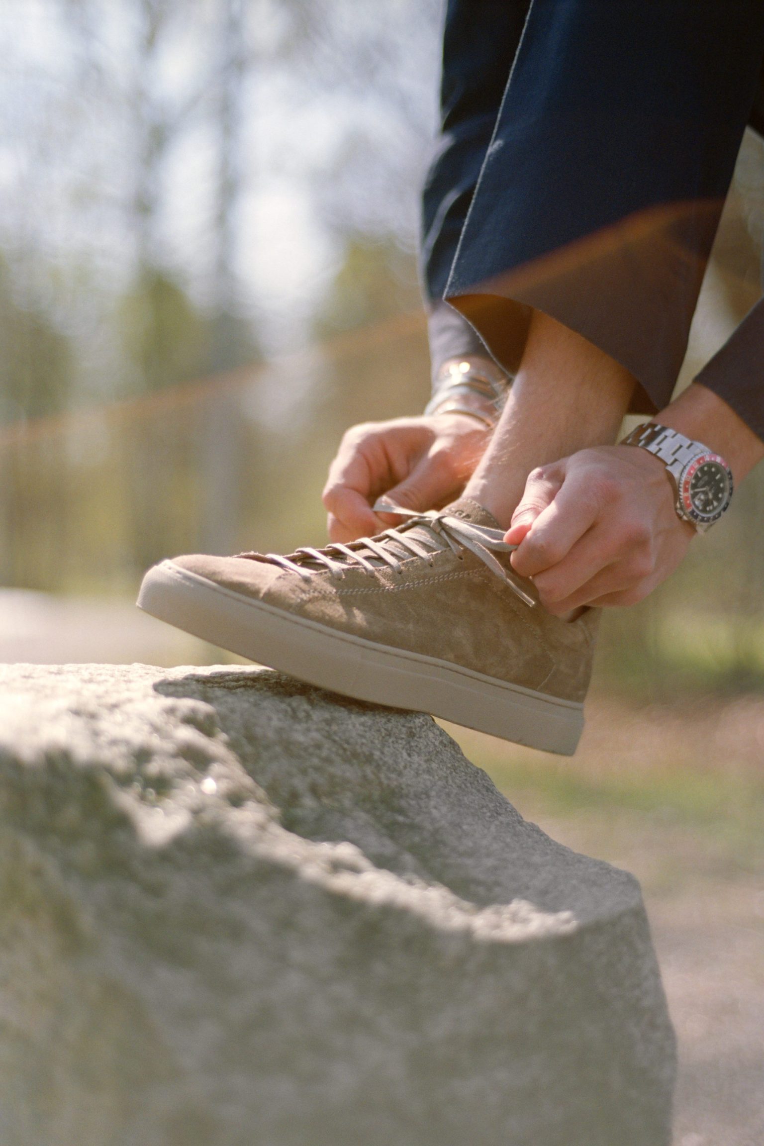 a person tying a shoelace on a rock