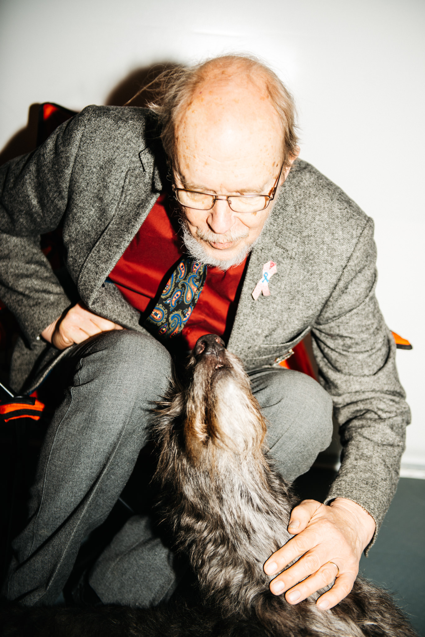 a man in a suit and tie petting a dog
