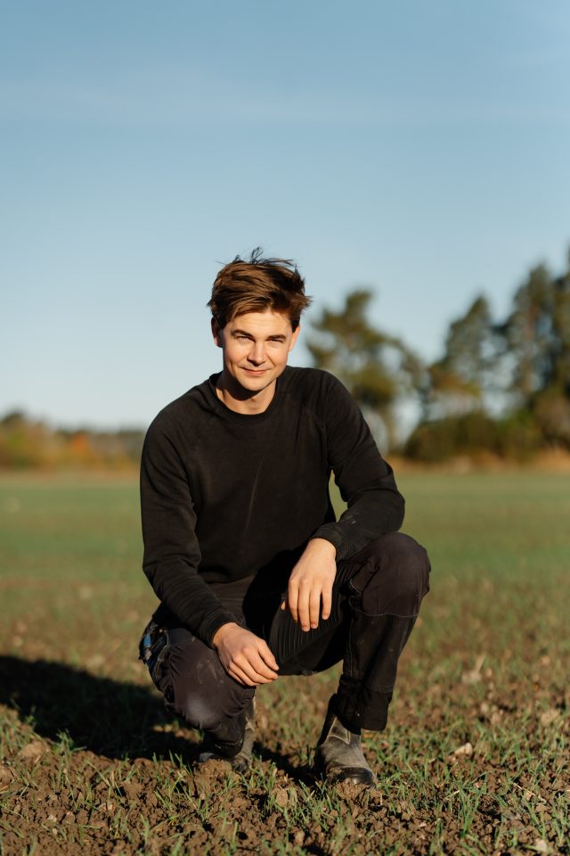 a man squatting in a field