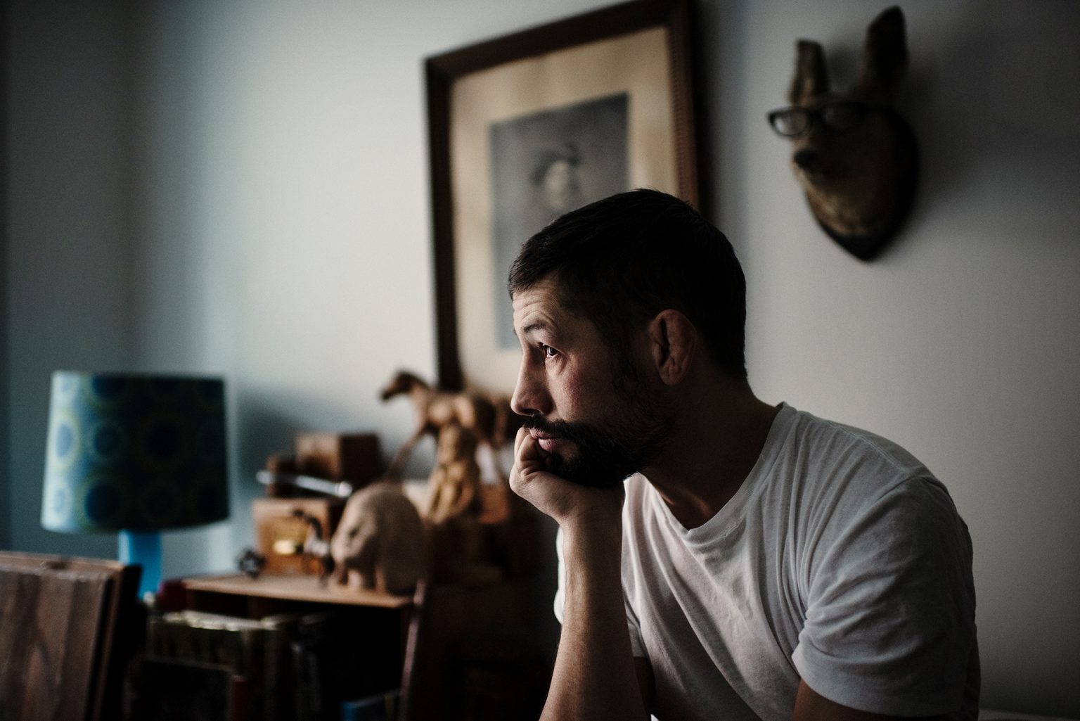 a man sitting in a room with his hand on his chin