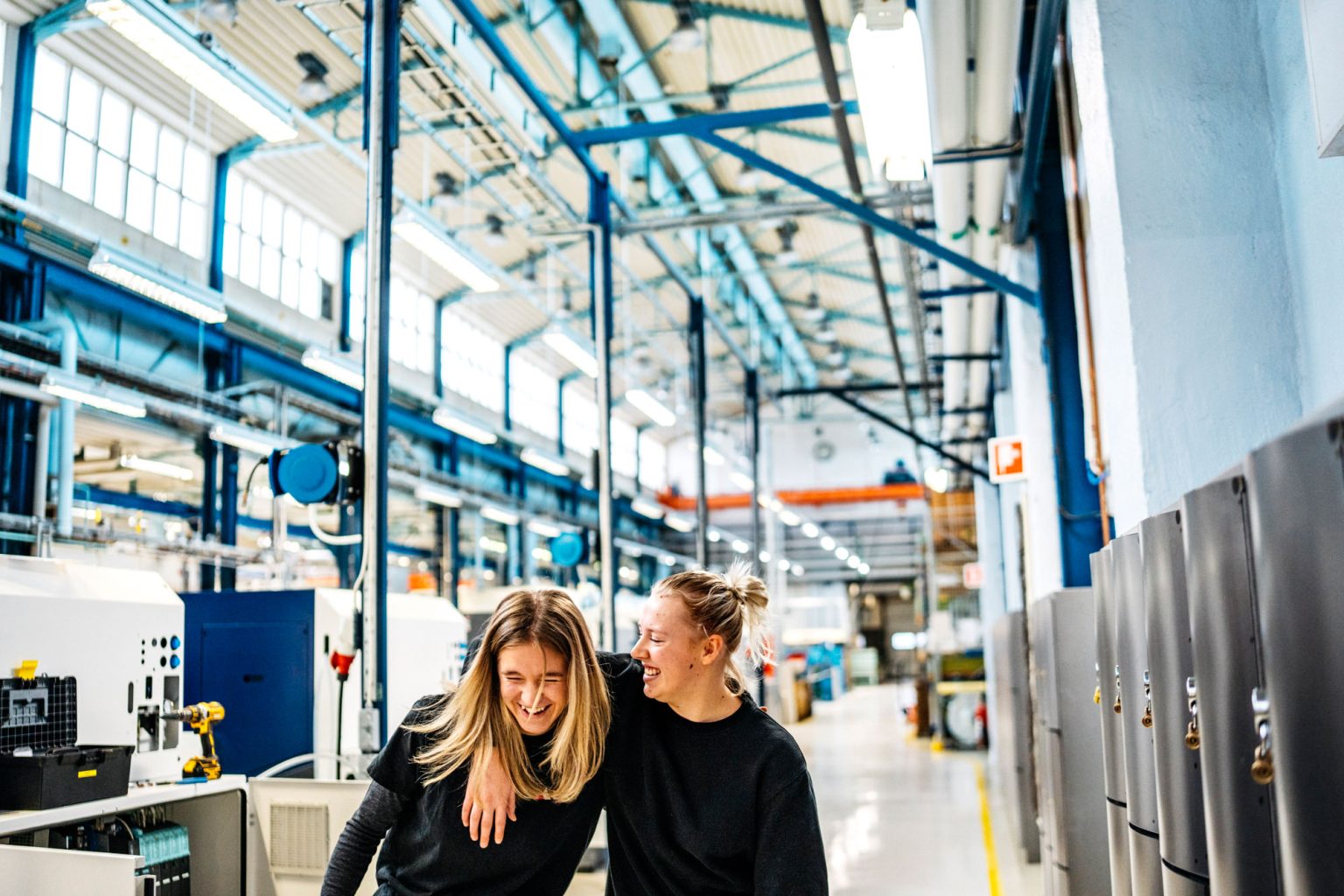 a woman laughing while another woman is touching her shoulder
