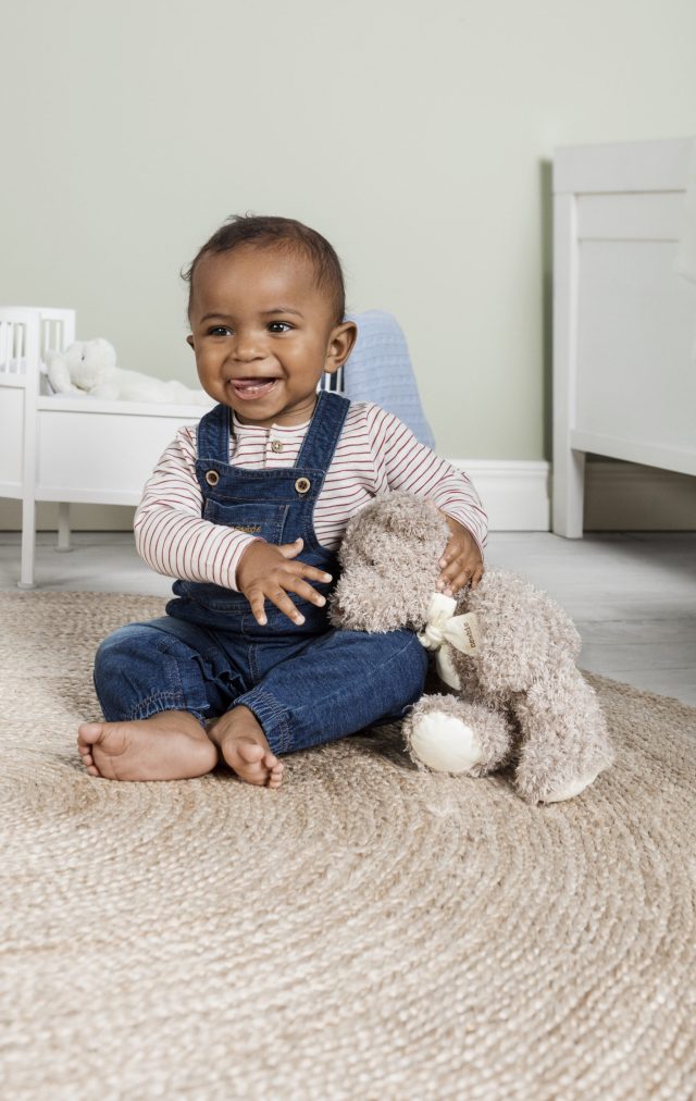 a baby sitting on a rug with a stuffed animal