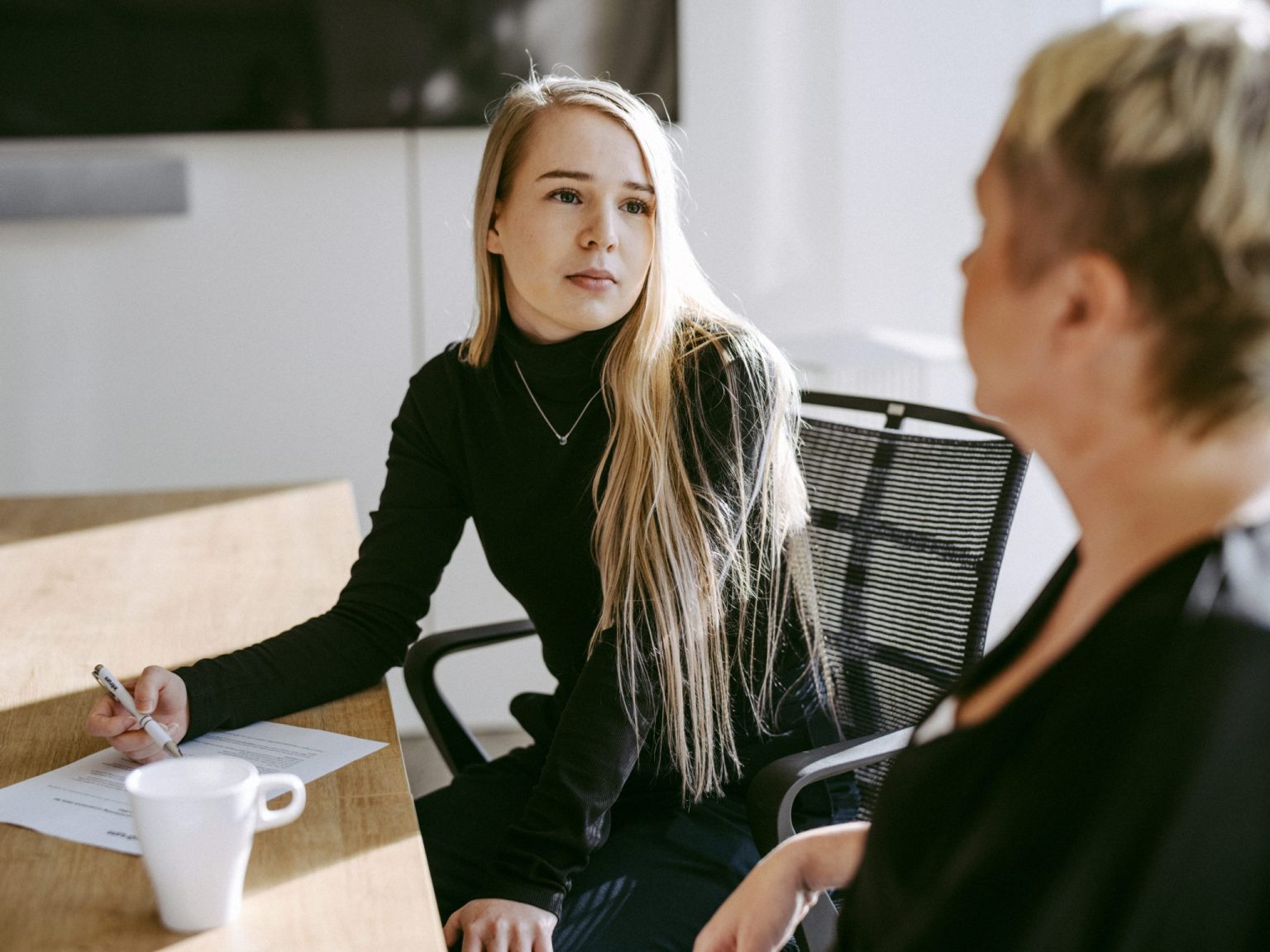 a woman sitting at a table with a woman in a black shirt