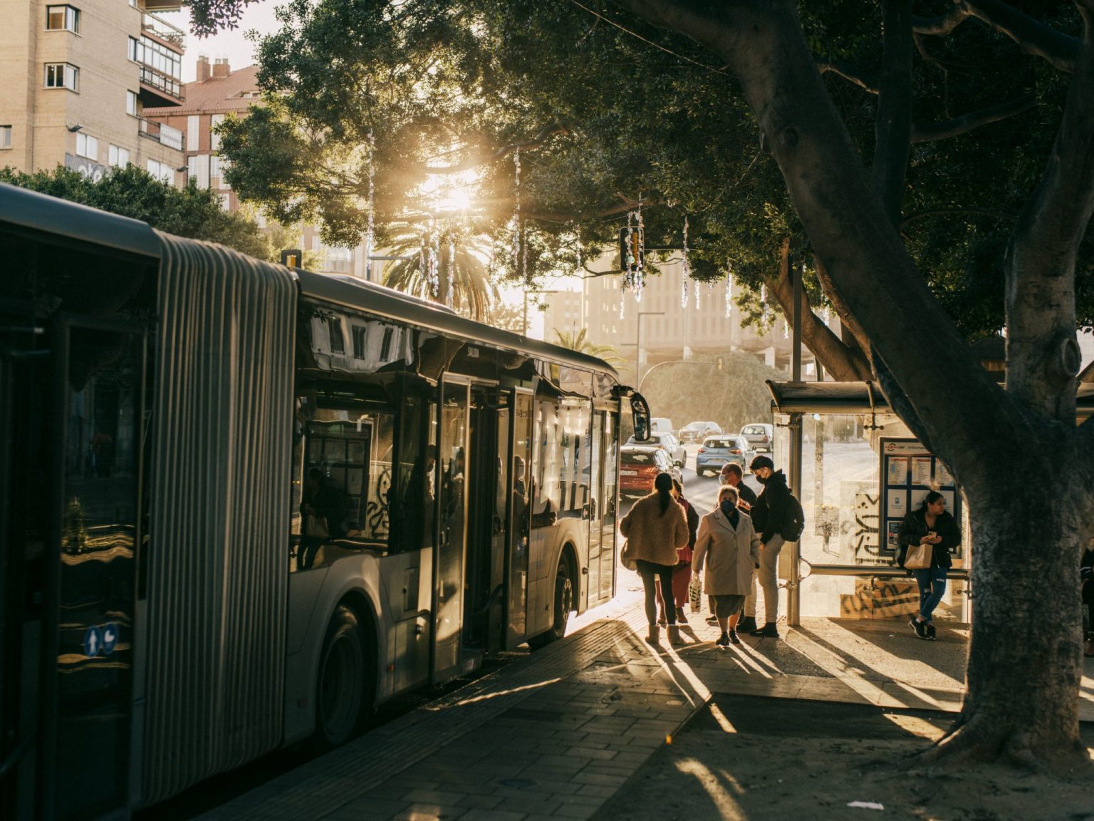 people walking on a sidewalk next to a bus