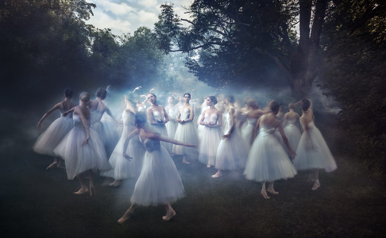 a group of women in white dresses dancing in the fog