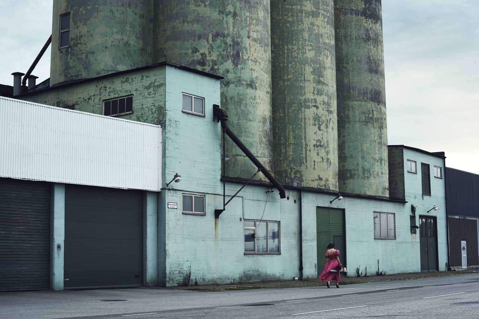 a woman walking down the street with a large building
