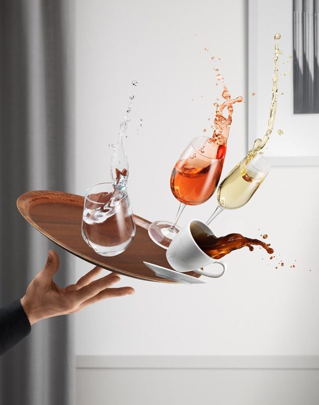 a hand holding a tray with glasses and cups