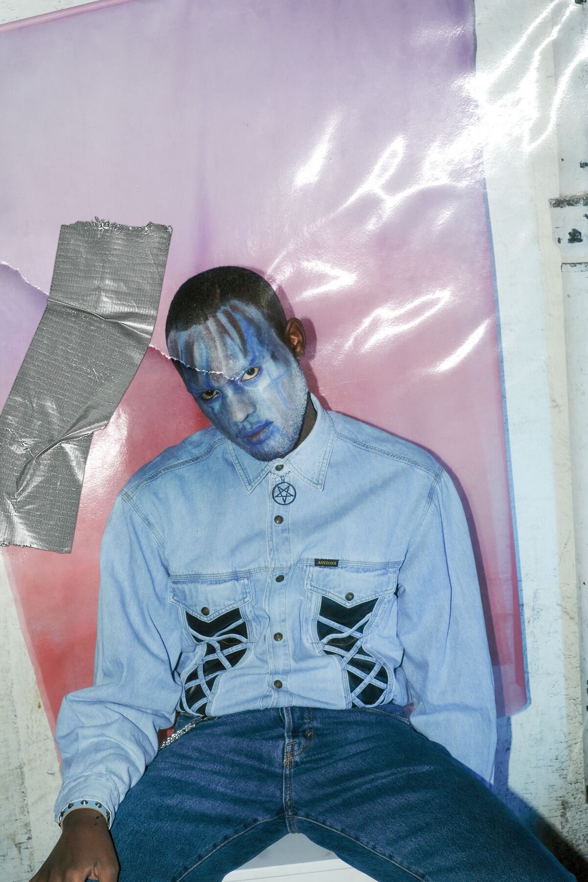 a man with blue face paint sitting on a poster