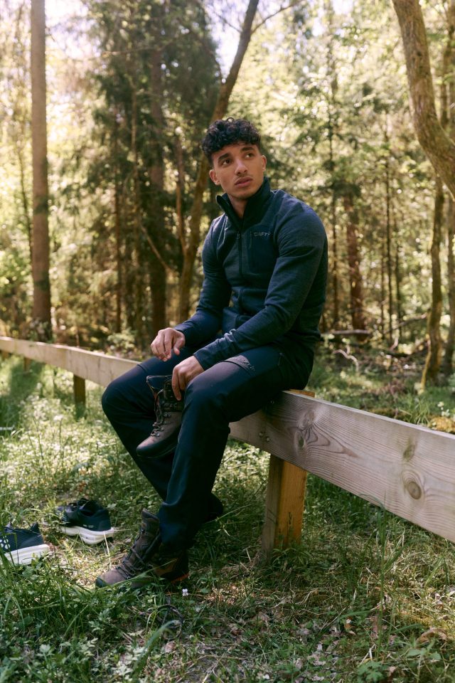 a man sitting on a fence in the woods
