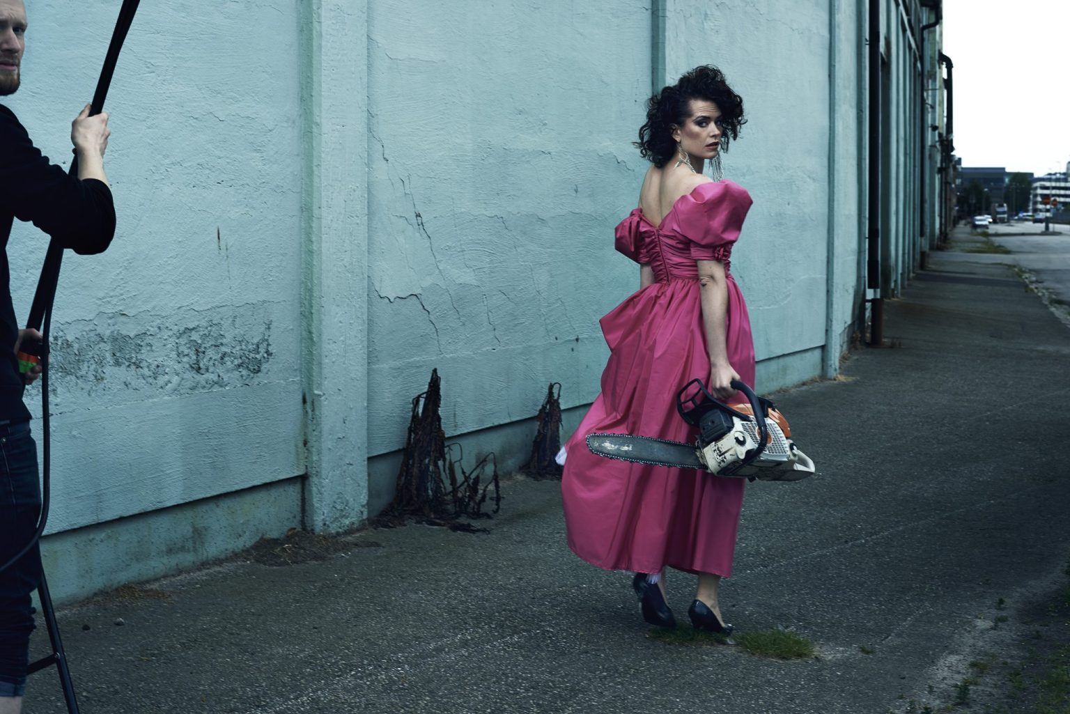 a woman in a pink dress holding a chainsaw