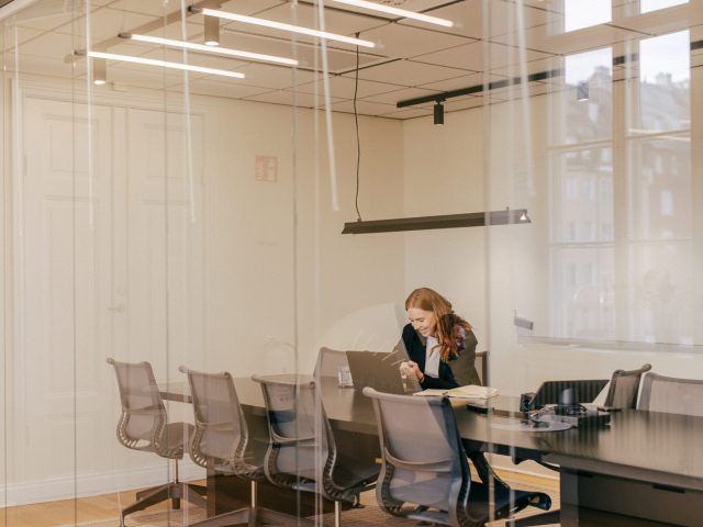 a woman sitting at a table looking at a laptop