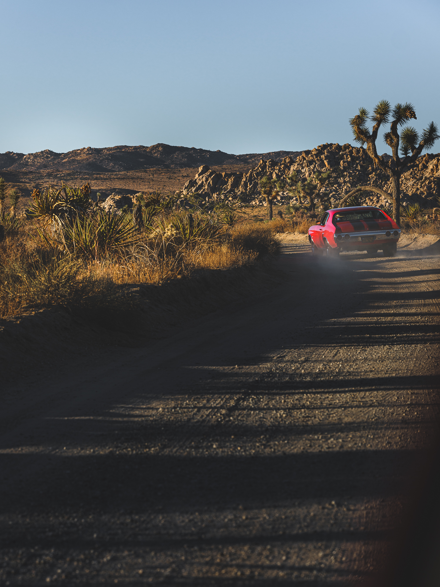 a red car driving on a dirt road