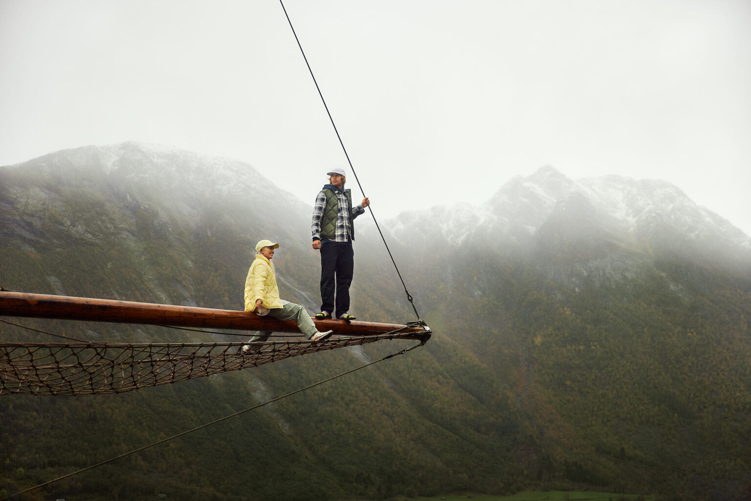 a man and woman sitting on a wooden beam