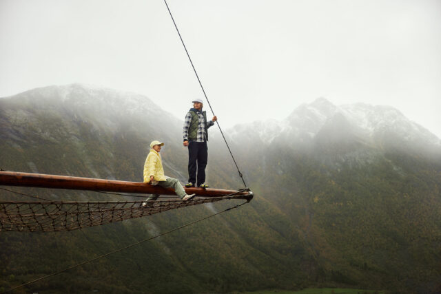 a man and woman sitting on a wooden beam