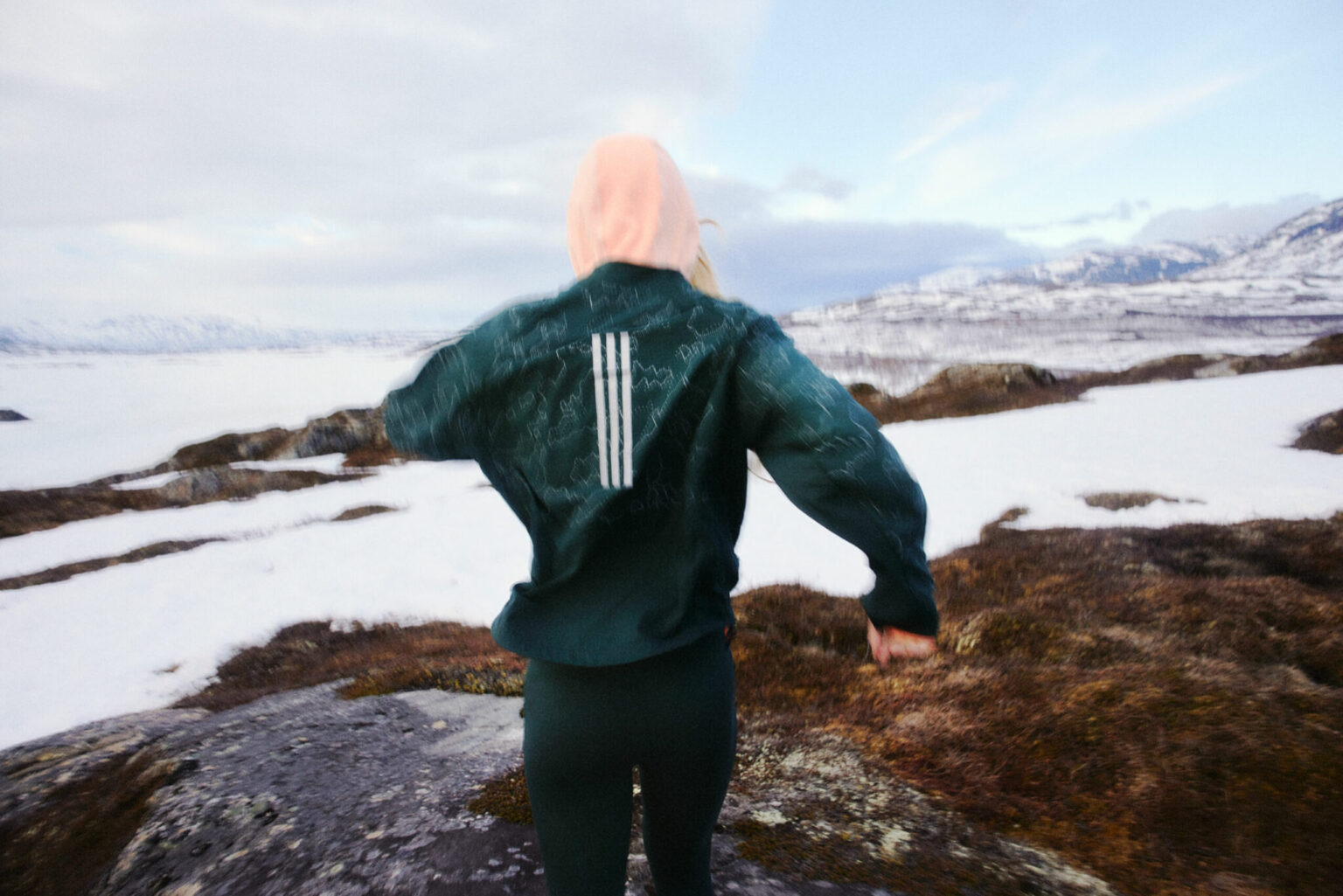 a person standing on a rocky surface with snow and mountains in the background