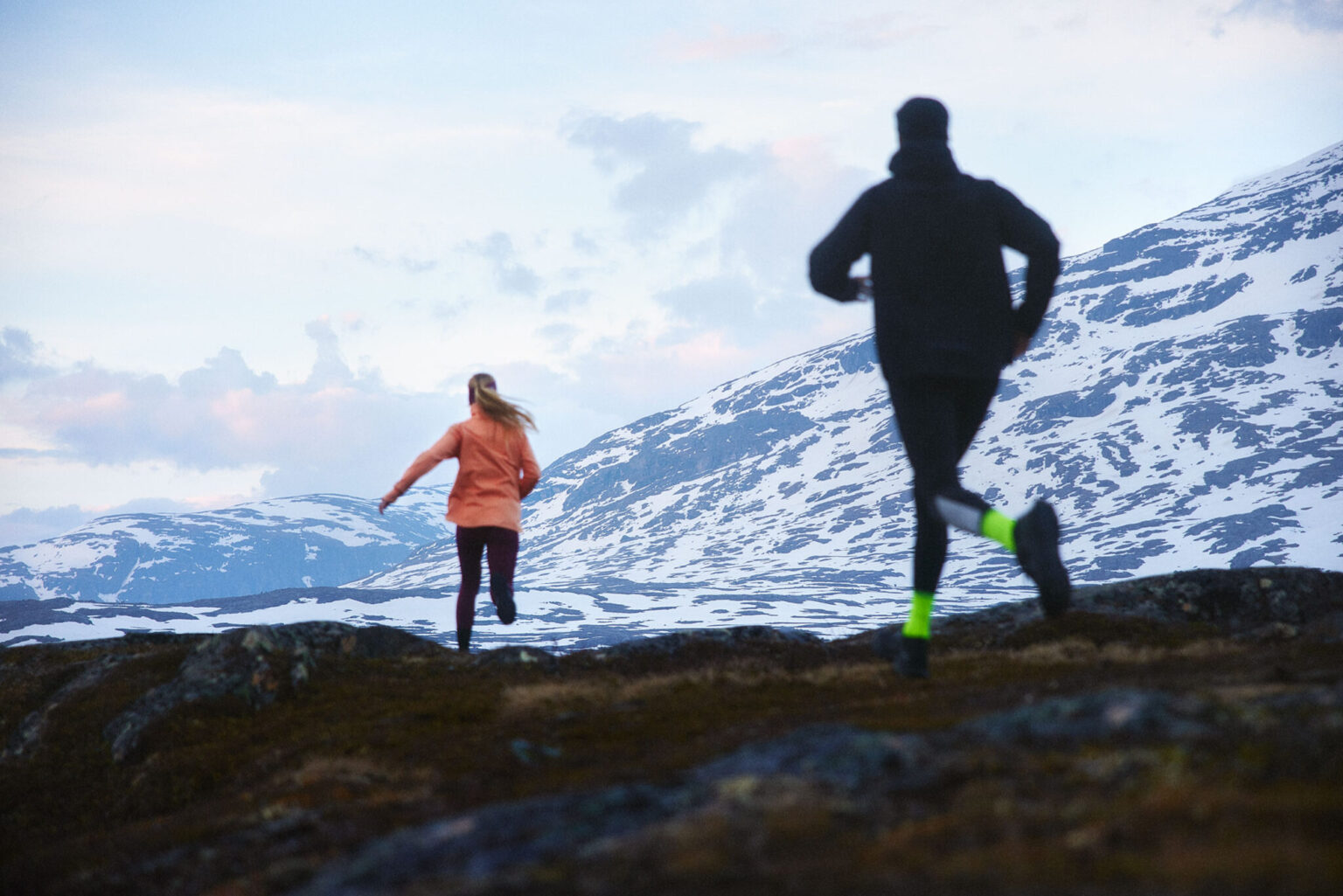 a couple of people running on a mountain