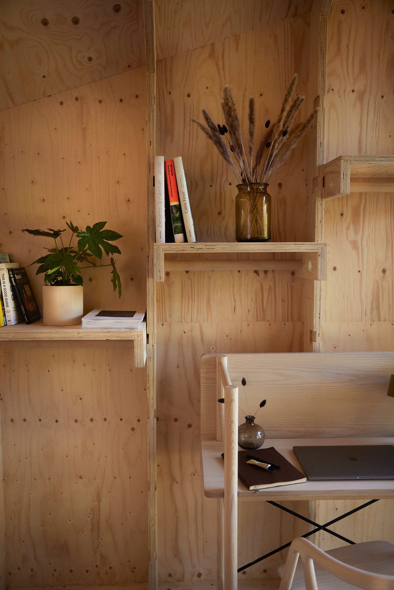 a wood wall with shelves and a vase of flowers
