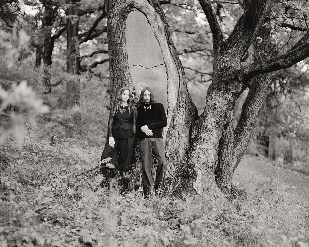 a man and woman standing next to a tree