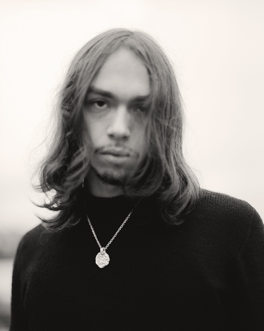 a man with long hair wearing a necklace