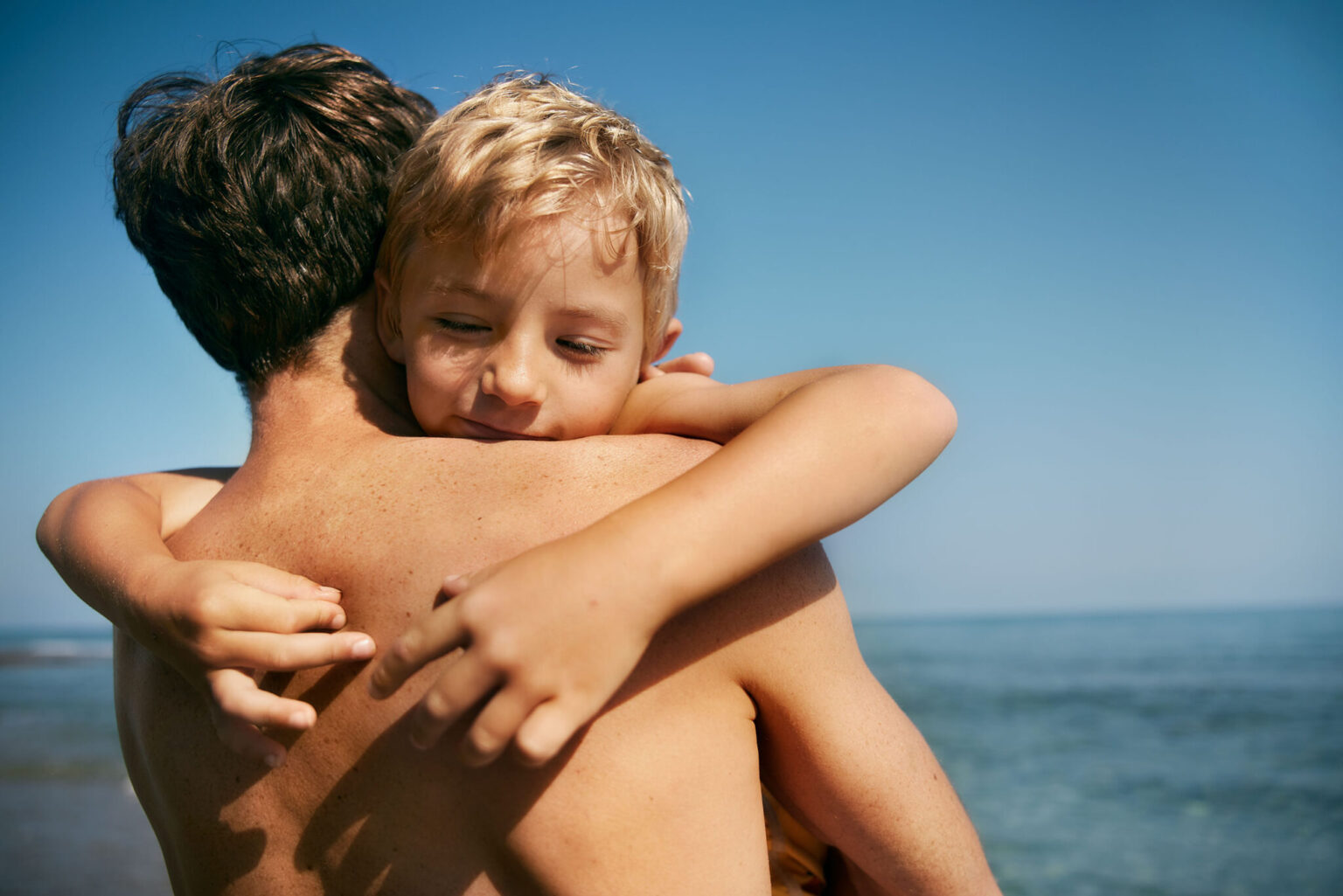 a man and child hugging on the beach