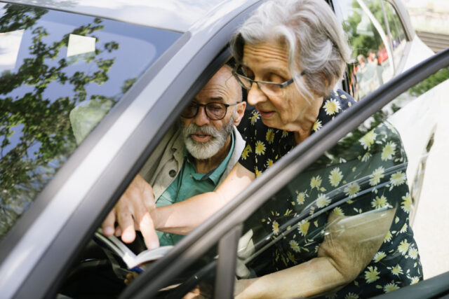 a man and woman looking at a book in a car