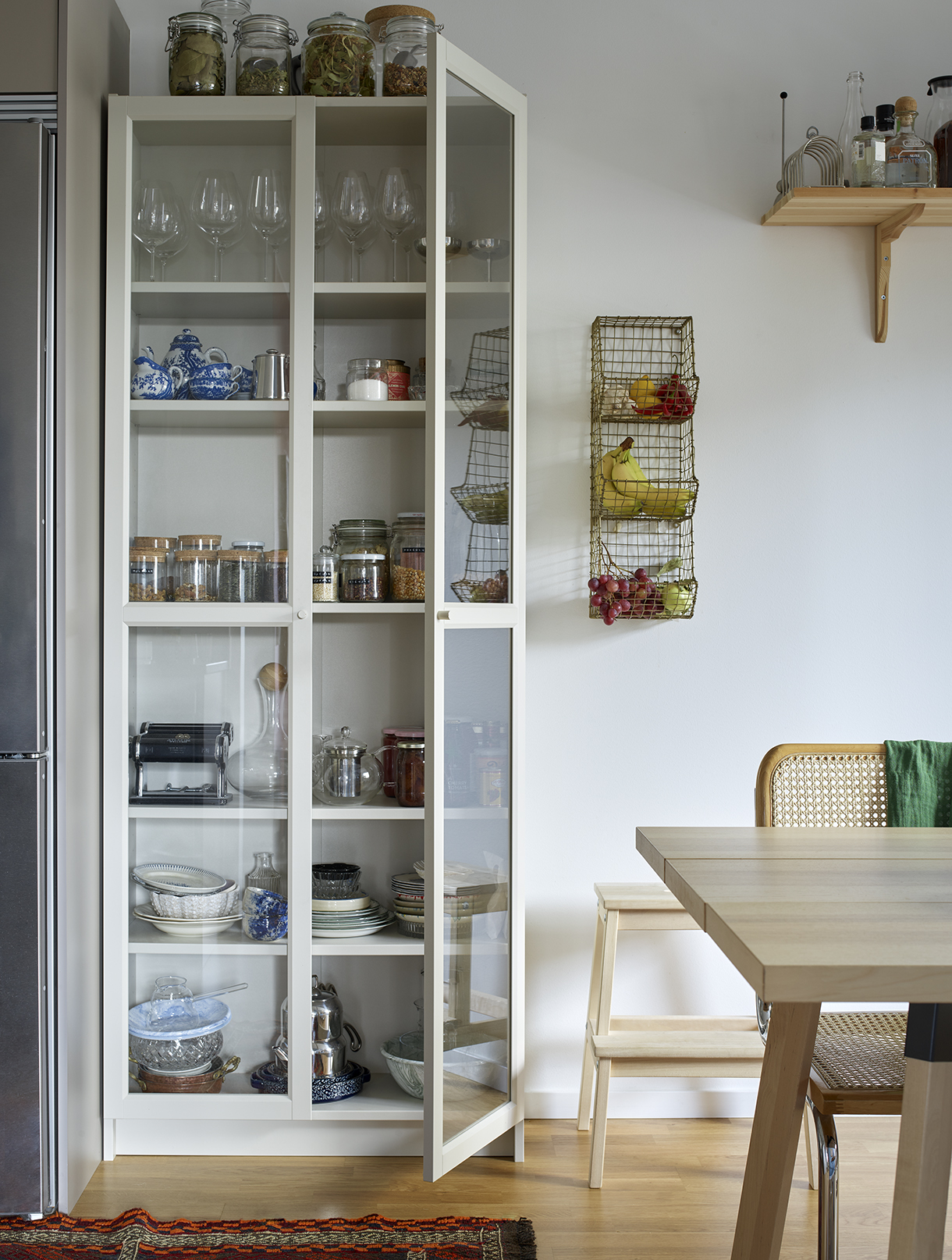 a white cabinet with glass shelves and a table
