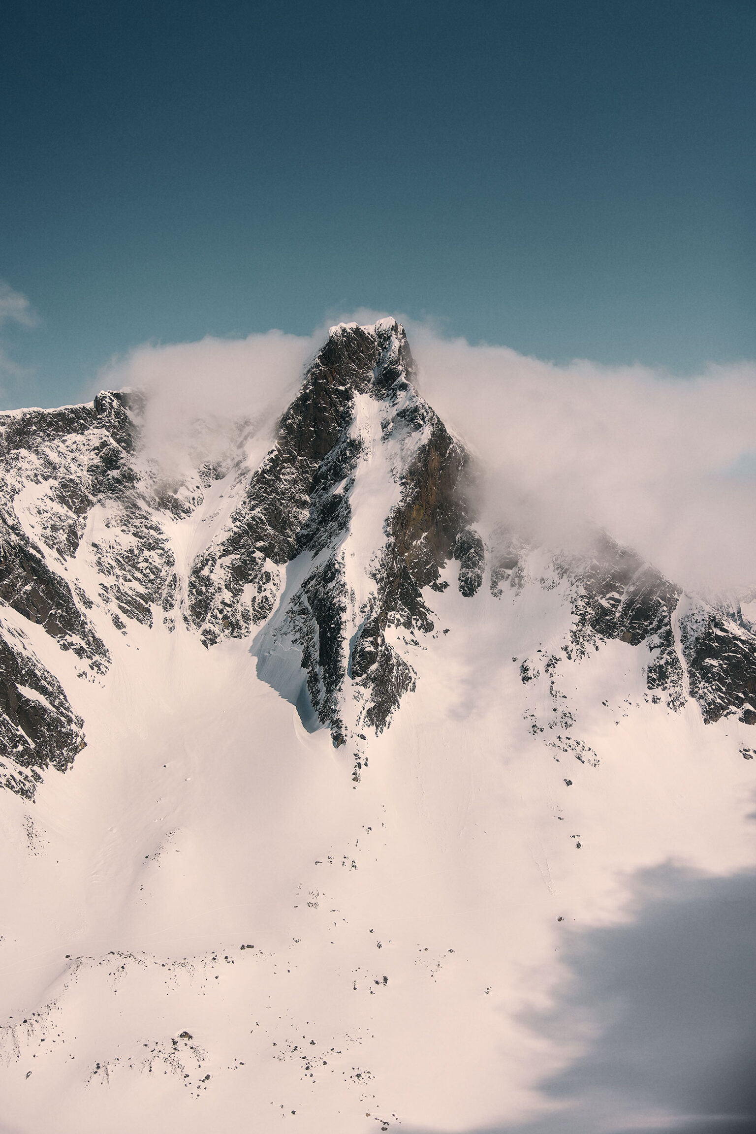 a mountain with snow and clouds