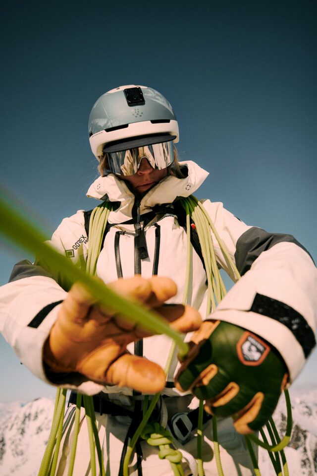 a person wearing a helmet and goggles holding a green rope